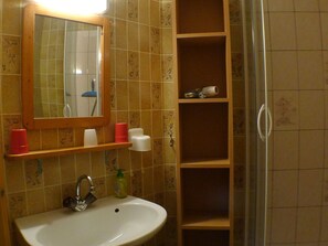 Casa de banho com uma pia branca, um espelho e um armário com produtos de higiene pessoal.