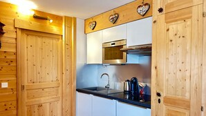 A compact kitchen with wooden cabinetry, a stainless steel oven, and a coffee maker.