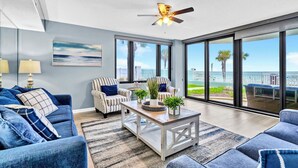 A modern living room with a large window, a ceiling fan, and a view of the ocean.