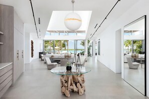 Ein modernes Interieur mit Esstisch, Sofas und einem großen Fenster mit Blick auf einen Strand.