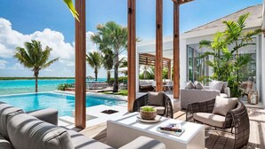 Ein Poolbereich mit Gartenmöbeln, einer Pergola und Blick auf das Meer.