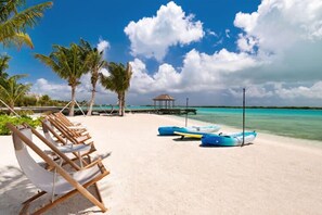 Uma praia com cadeiras de praia, um gazebo e barcos azuis.