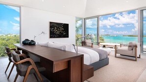 Ein modernes Schlafzimmer mit einem großen Bett, einem Schreibtisch und Meerblick.