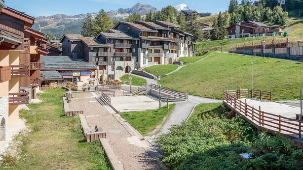 A mountain resort with wooden buildings, a restaurant, and a ski lift.