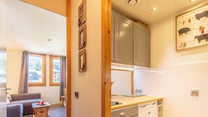 A compact kitchen with a sink, cabinets, and a dining area with a table and chairs.