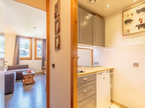 A compact kitchen with a sink, cabinets, and a dining area with a table and chairs.