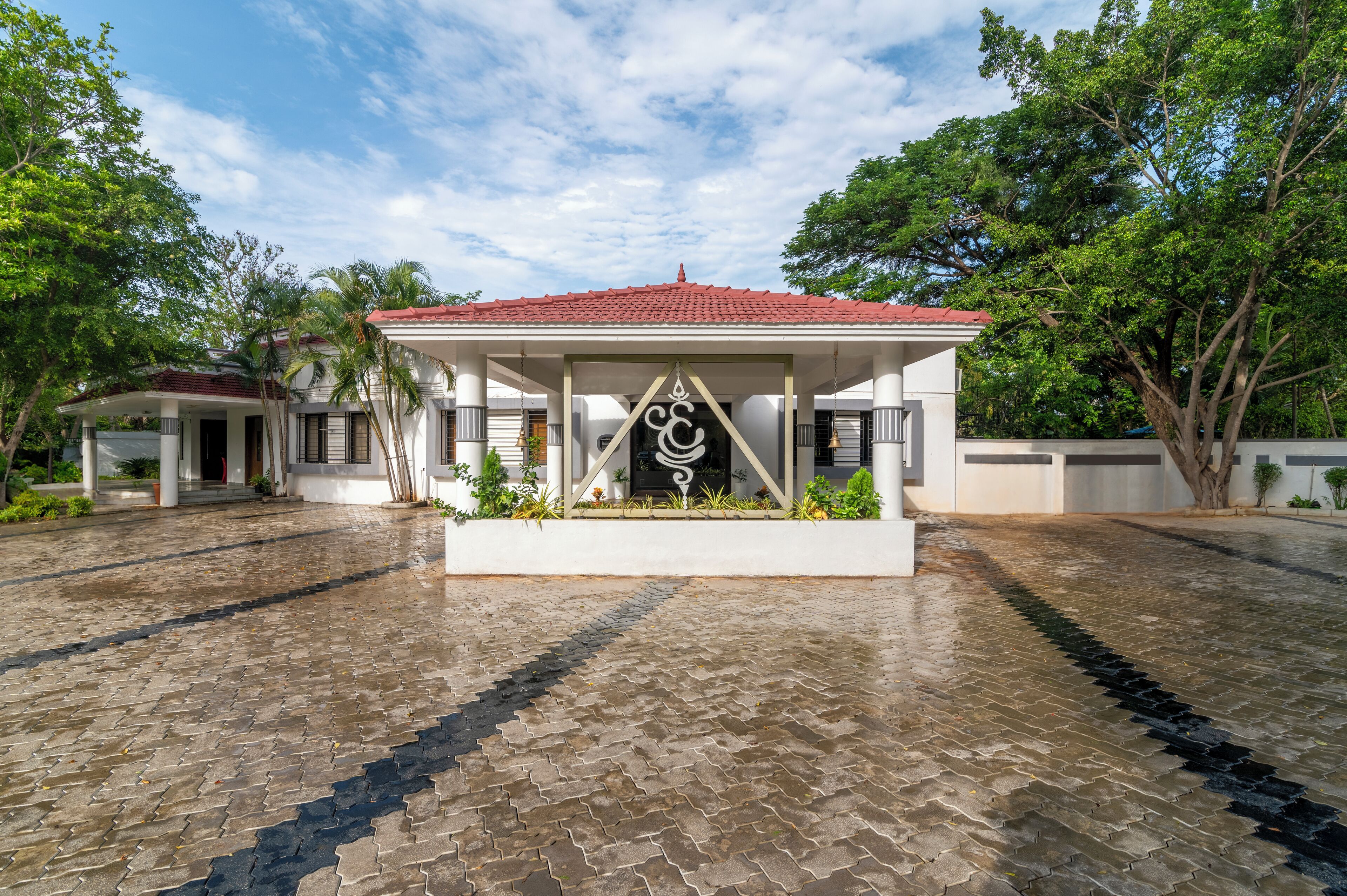 A covered pavilion with a tiled roof, surrounded by a paved area with a decorative pattern.