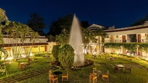 A courtyard with a central fountain, surrounded by outdoor seating and a building with multiple windows and balconies.