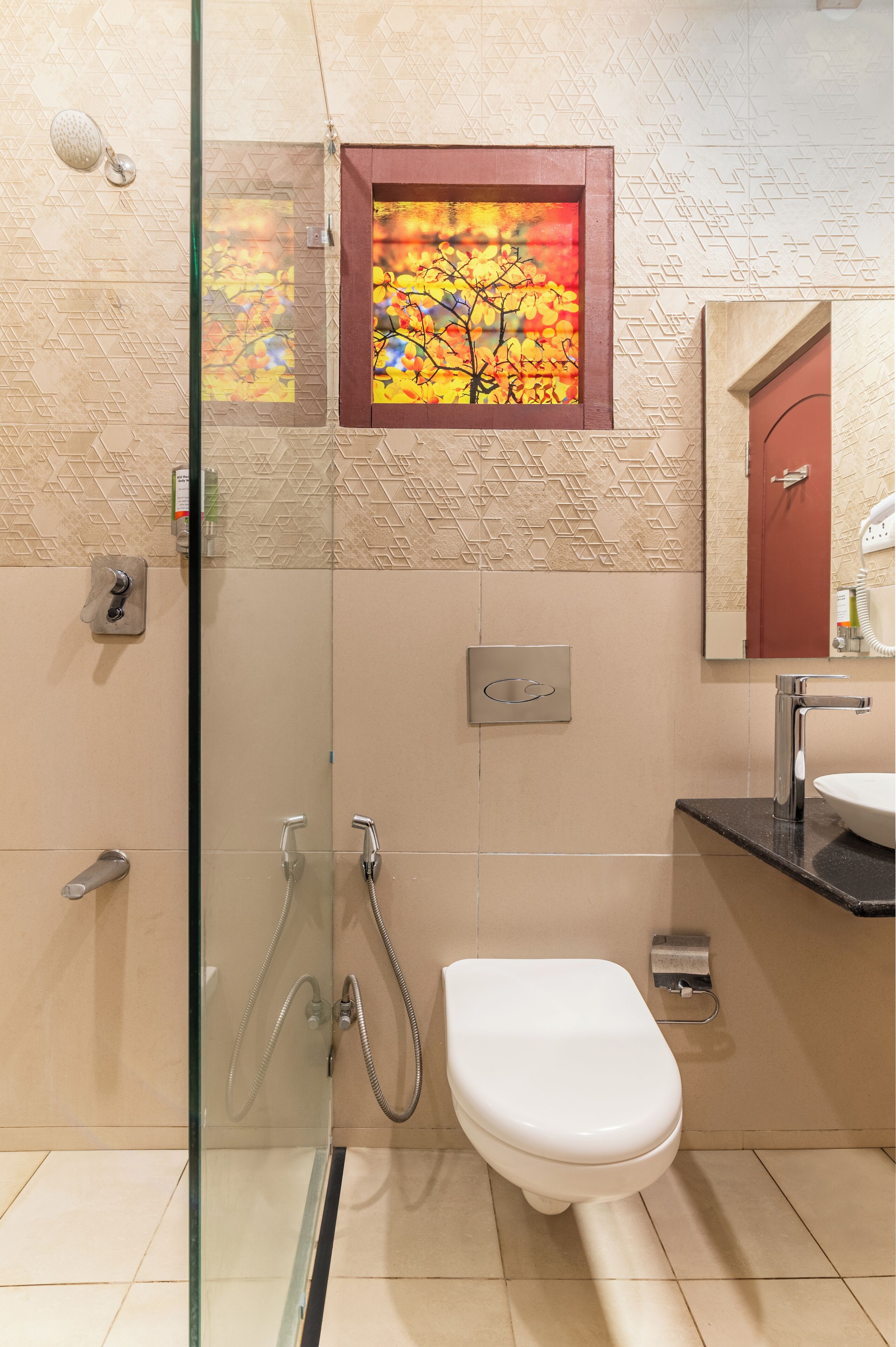Un baño moderno con mampara de cristal, inodoro blanco y un ventanal con vistas coloridas.