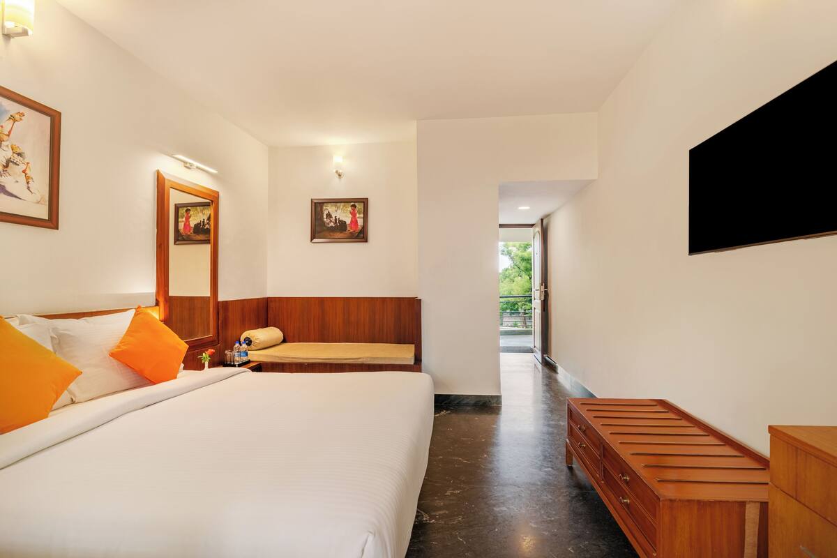 Ein modernes Hotelzimmer mit einem großen Bett, einer hölzernen Sitzbank und einem am Wand montierten Flachbildfernseher.