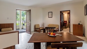 A modern dining area with a wooden table, two beige sofas, and a wooden cabinet.