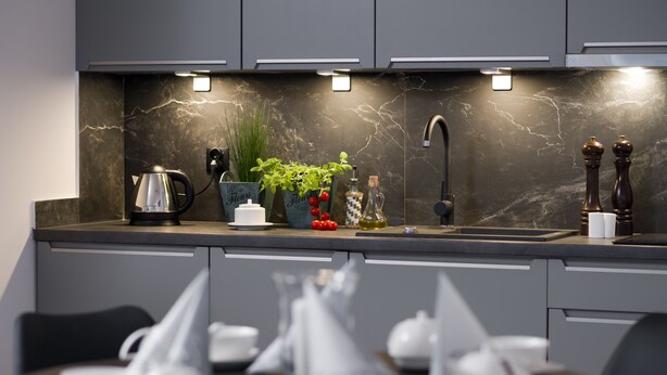 Una cocina moderna con salpicadero de mármol, electrodomésticos de acero inoxidable y un lavamanos empotrado.