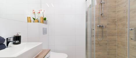 A modern bathroom with a white sink, toilet, and shower.