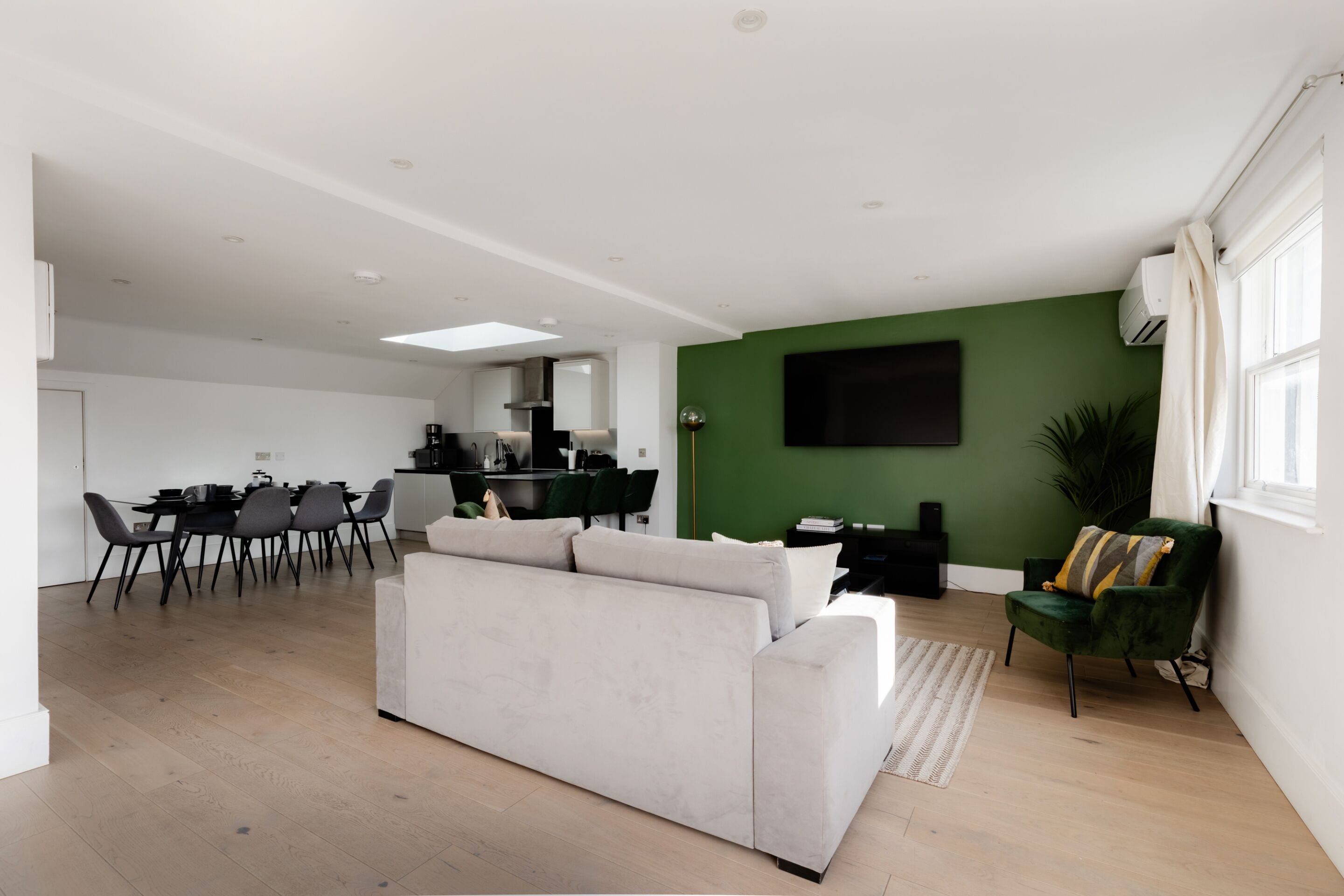 A modern living room with a sofa, dining area, and kitchen in the background.