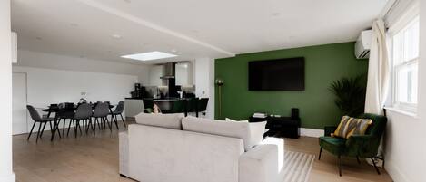 A modern living room with a sofa, dining area, and kitchen in the background.