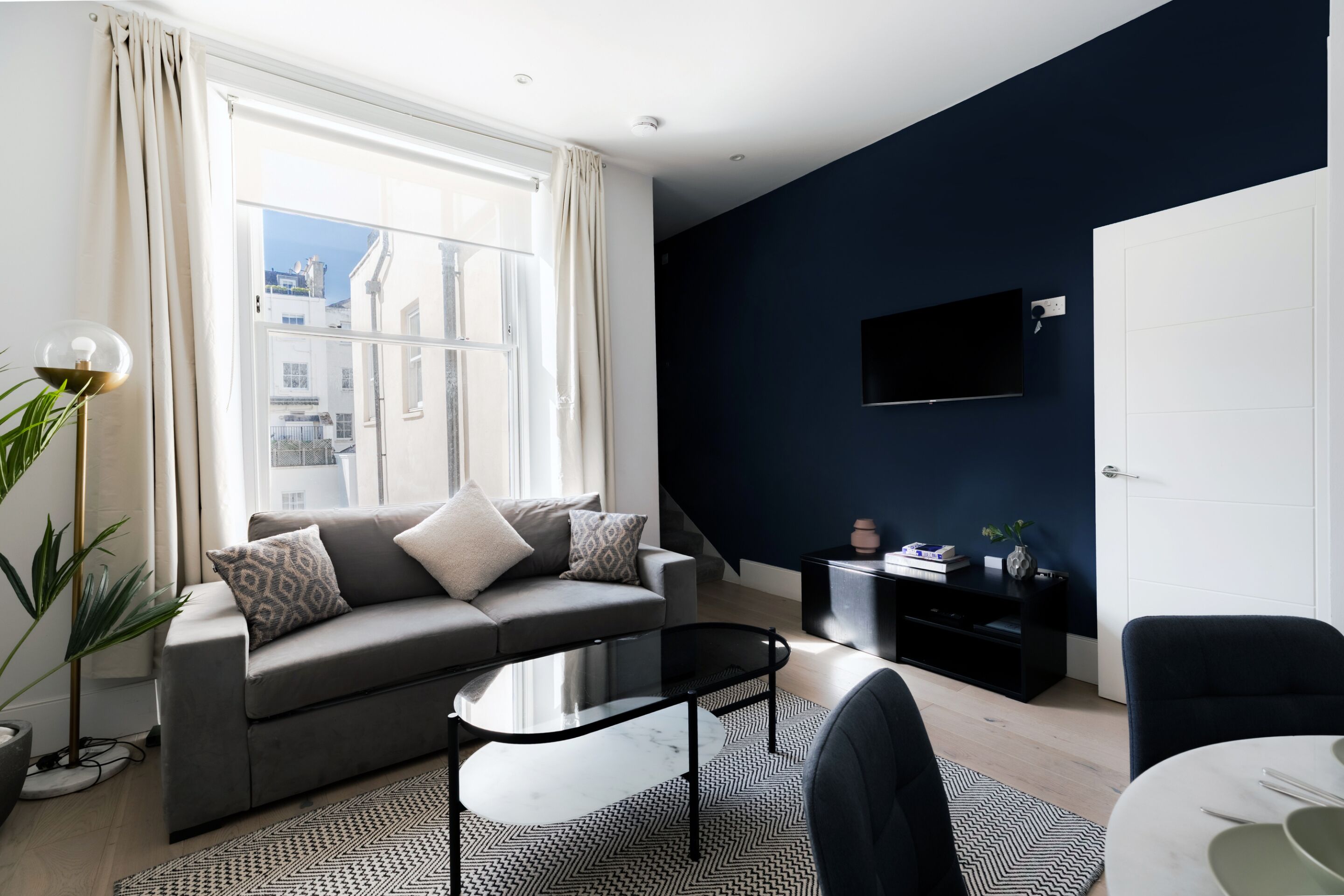 A modern living room with a sofa, coffee table, and a TV mounted on the wall.