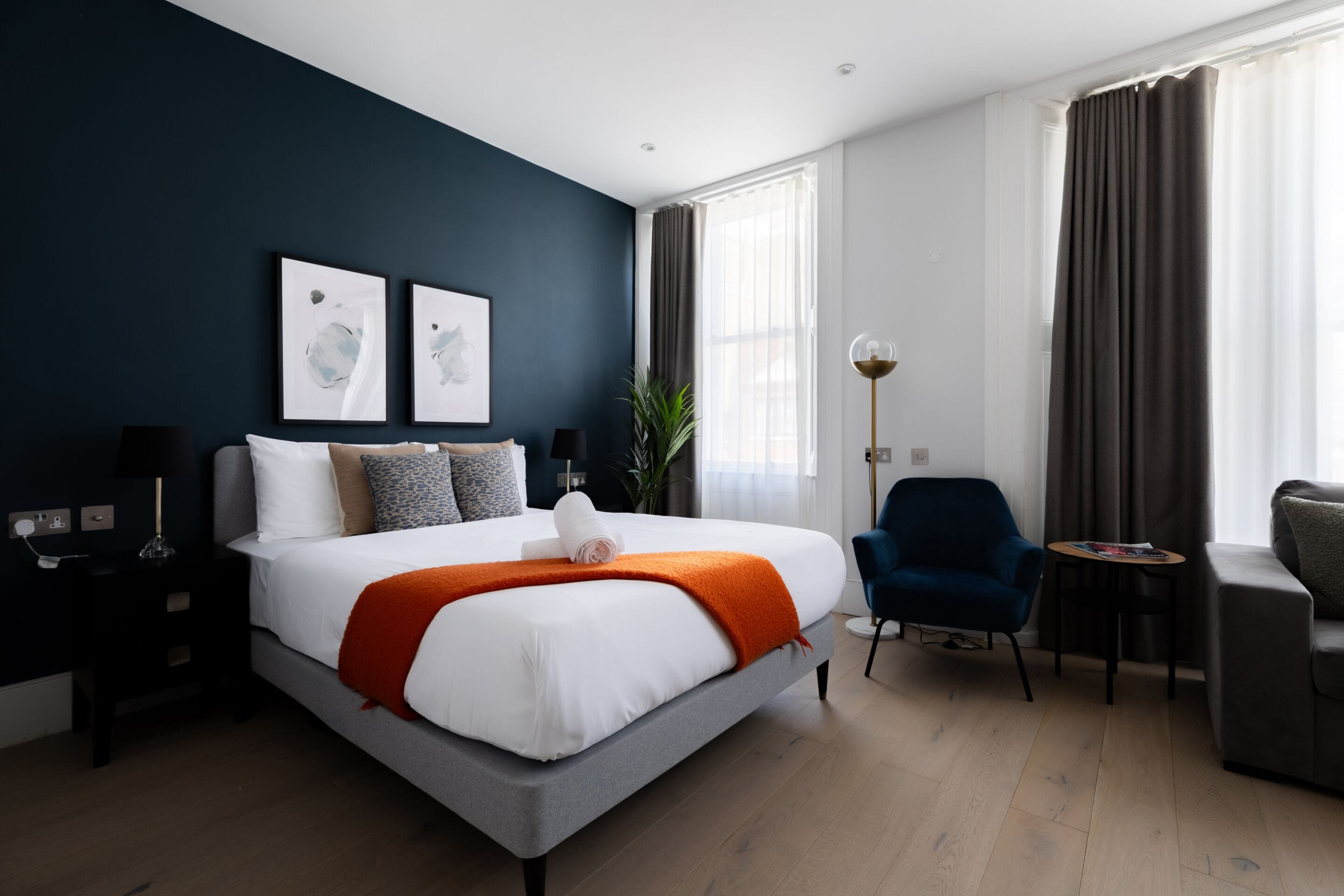 Una habitación de hotel moderna con una cama grande, un escritorio, una silla y una mesita.