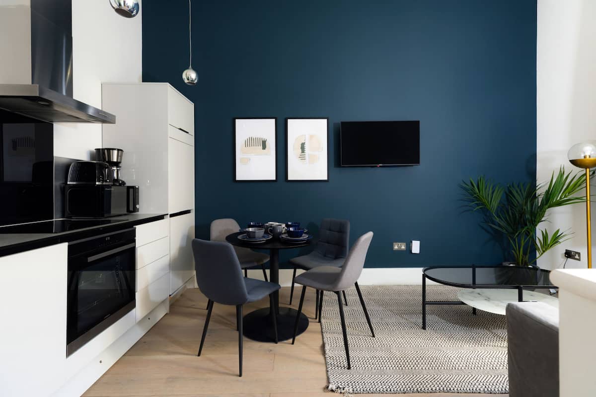 A modern kitchen with a dining area, a flat-screen TV, and a potted plant.