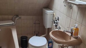 A bathroom with a bathtub, toilet, sink, and skylight. - Apartment COLIN (Bremerhaven)