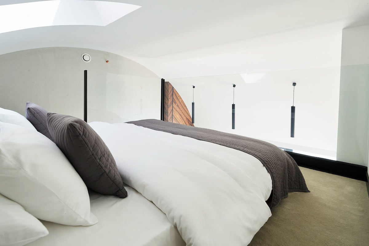 Een moderne hotelkamer met een groot bed, een raam met gordijnen en een dakvenster.