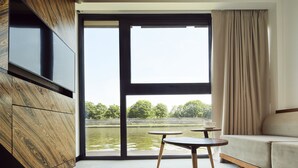 A modern room with a large window, a sofa, and two small tables. - New Port Hotel (Kraków)