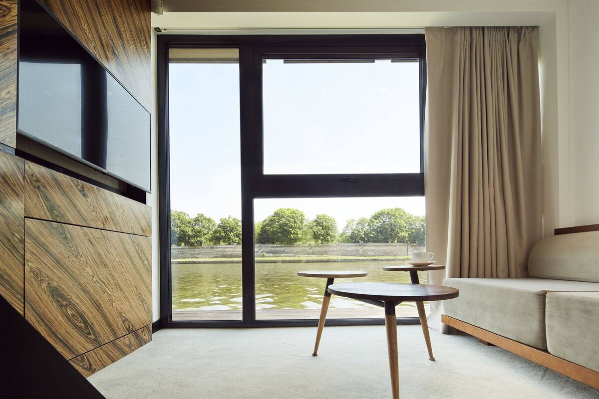 A modern room with a large window, a sofa, and two small tables.