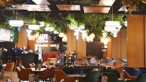 A restaurant with multiple dining tables and chairs, overhead lighting fixtures, and a ceiling with exposed beams and industrial elements. - New Port Hotel (Kraków)