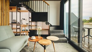 A modern living room with a sofa, coffee table, and TV. - New Port Hotel (Kraków)