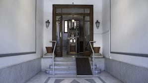 A marble staircase with a wooden door at the top, leading to an interior space.