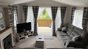 Ein gemütliches Wohnzimmer mit Fernseher, Sofa und Kamin.