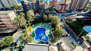 Un hôtel doté d’une piscine, de palmiers et offrant une vue sur la mer.