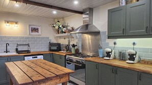 Uma cozinha com mesa de madeira, forno embutido, fogão e pia.