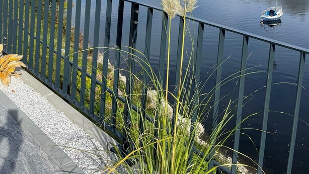 A river view with a dock, a boat, and a railing. - Ferienhaus mit 6 Apartments, Terrasse und Blick auf den Stausee (Bad Lobenstein)