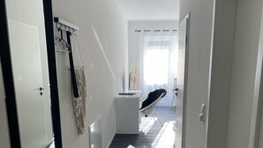 A modern hotel corridor with a dark wood floor, white walls, and a large mirror on the left. - Ferienhaus mit 6 Apartments, Terrasse und Blick auf den Stausee (Bad Lobenstein)