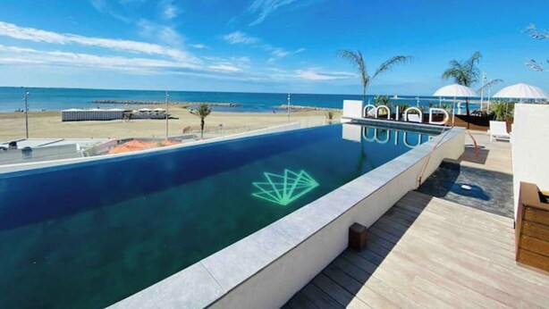Una piscina infinita en la azotea con vistas despejadas a la playa y al océano.