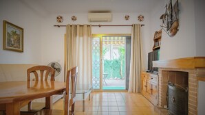 A dining area with a wooden table and chairs, a fireplace, and a view through a glass door to an outdoor area. - Ola Azul bungalow V (Benidorm)
