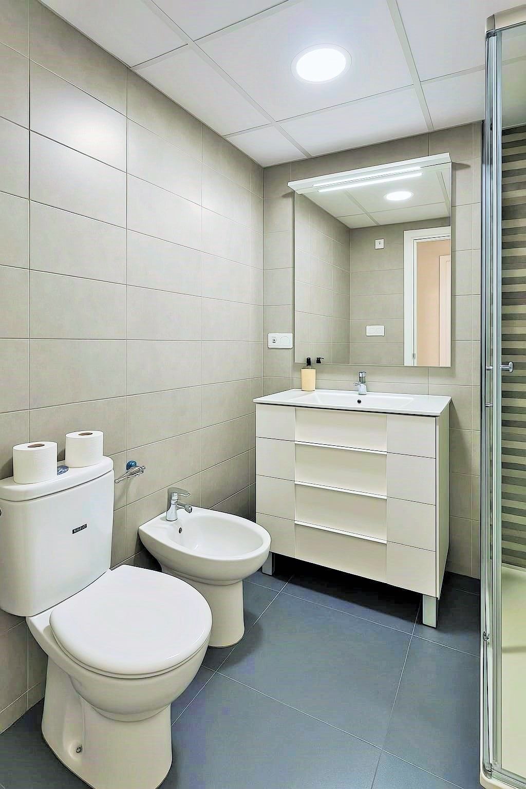 A modern bathroom with a toilet, bidet, and sink.
