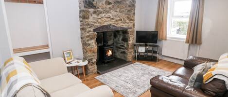 A living room with a stone fireplace, a sofa, a leather couch, and a television.