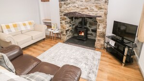 Un salon chaleureux avec une cheminée en pierre, un canapé beige, un divan en cuir marron et un téléviseur à écran plat.