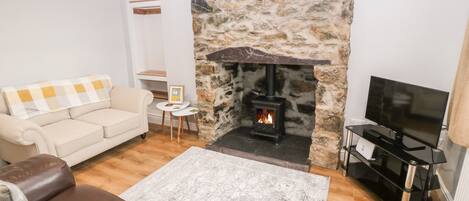 A cozy living room with a stone fireplace, a beige sofa, a brown leather couch, and a flat-screen TV.