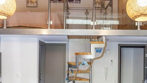 Un intérieur moderne avec un escalier, des poutres en bois et un coin repas.