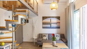Un salon moderne avec un escalier, un canapé, une table basse et un tableau représentant un pont.