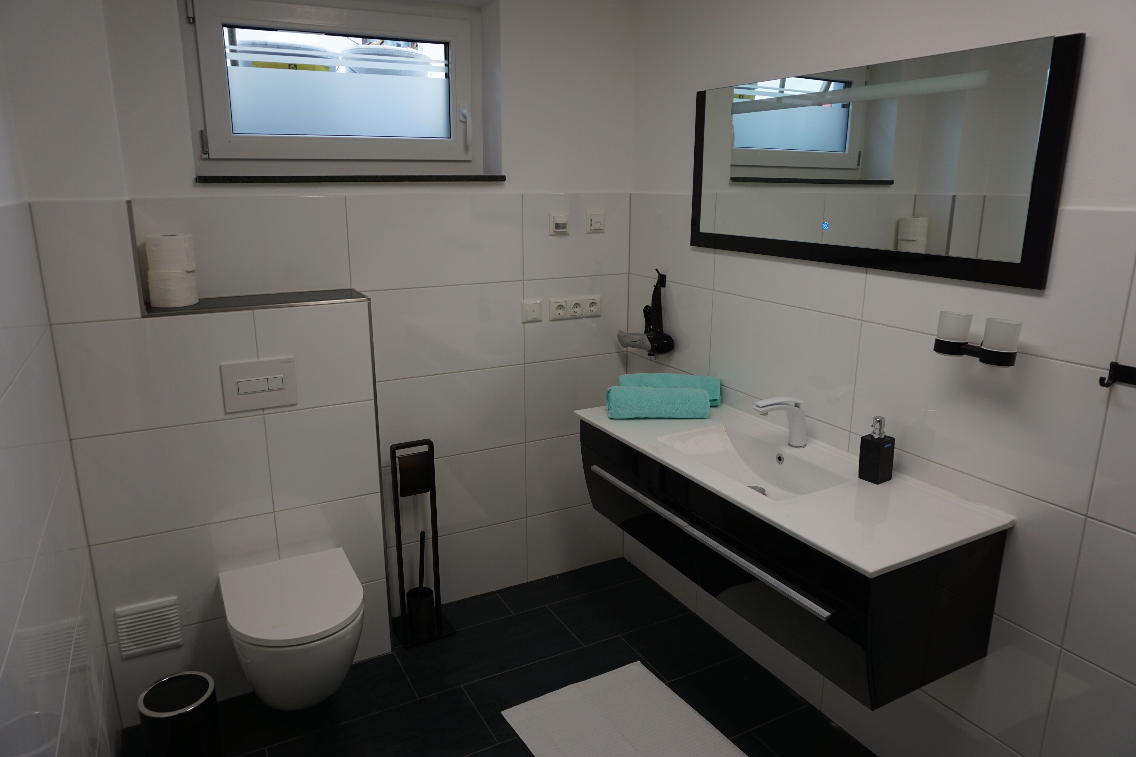 Une salle de bain moderne avec des toilettes, un lavabo et un miroir.