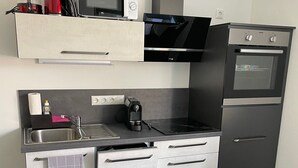 Ett kompakt kök med mikrovågsugn, kaffebryggare och ugn.