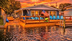A waterfront house with a dock, blue chairs, and an American flag. - Family & Pet-Friendly River Escape w/ Kayaks, Manatees & Outdoor Fun! (Weeki Wachee)