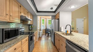 A kitchen with wooden cabinets, a granite countertop, a stainless steel refrigerator, and a dishwasher. - "The Mint" @ Margaritaville Lake Resort, Boating, Golfing, Fire Pit, Swimming (Osage Beach)