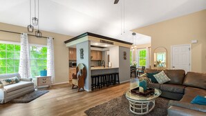 A spacious living room with a sofa, a coffee table, and a dining area with a bar. - "The Mint" @ Margaritaville Lake Resort, Boating, Golfing, Fire Pit, Swimming (Osage Beach)