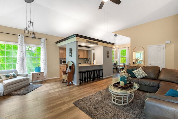 A spacious living room with a sofa, a coffee table, and a dining area with a bar.