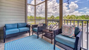 A covered porch with a blue patterned rug, wicker furniture, and a view of the sky and clouds. - Two Minutes to Beach. Includes Taxi Bikes, Lake View, and Community Pool (Santa Rosa Beach)