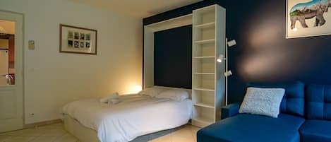 A bedroom with a bed, a blue sofa, a built-in wardrobe, and a framed picture on the wall.